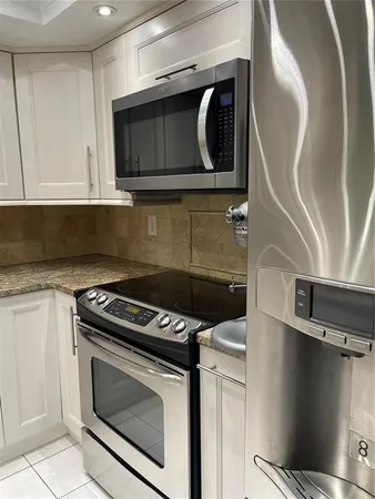 a kitchen with granite countertop a stove top oven microwave and cabinets