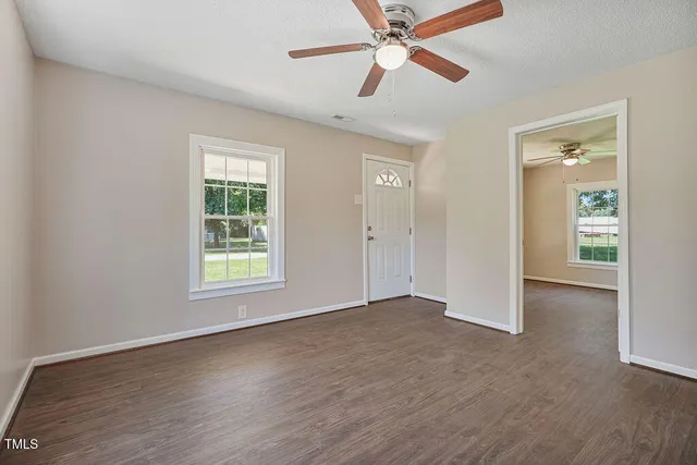 an empty room with wooden floor closet and windows
