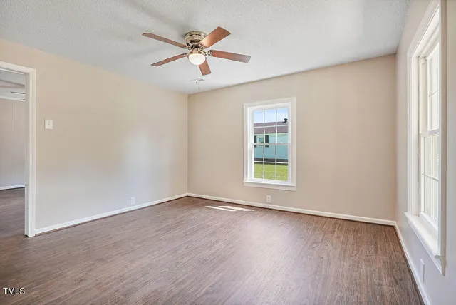 an empty room with wooden floor and windows