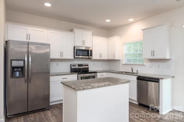 a kitchen with stainless steel appliances granite countertop a refrigerator sink and microwave