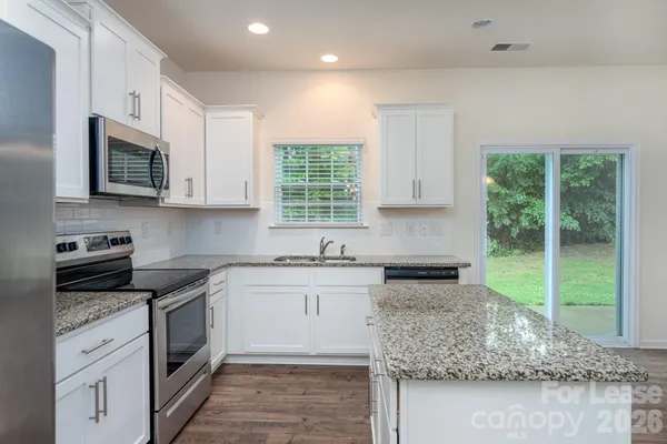 a kitchen with kitchen island granite countertop white cabinets and a window
