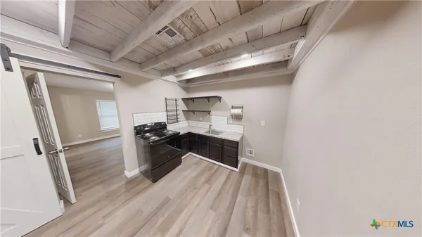 a kitchen with a sink and wooden floor