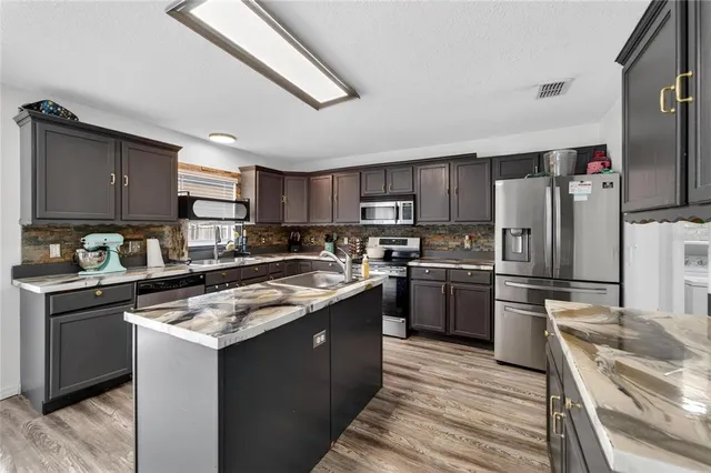 a kitchen with stainless steel appliances granite countertop a stove a sink and a microwave