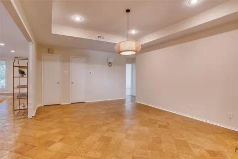 an empty room with kitchen view and a chandelier fan