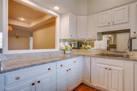 a kitchen with stainless steel appliances granite countertop a sink a stove and white cabinets with wooden floor