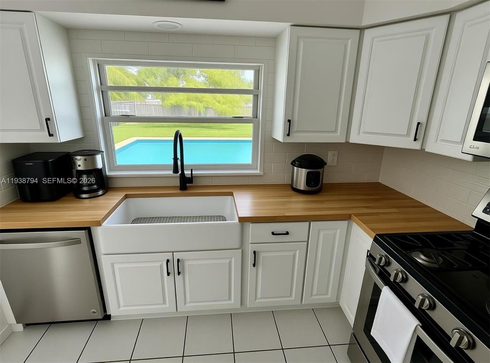 9955 Southwest 214th Street Cutler Bay, FL 33189 - Photo 5 of 15 a kitchen with white cabinets a sink and a stove with wooden floor