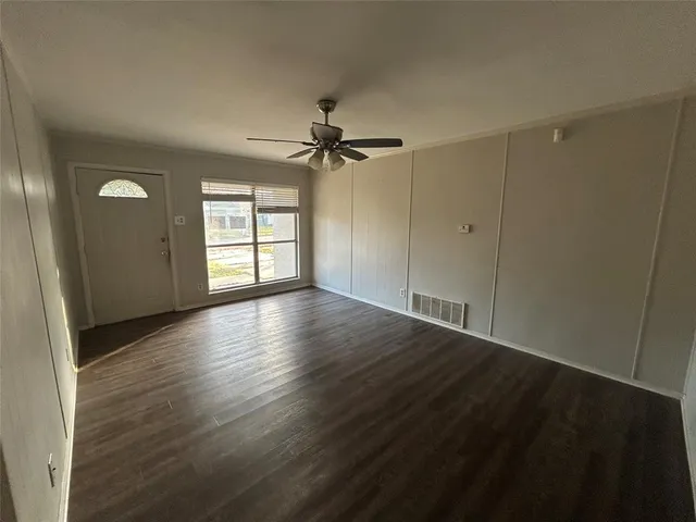 a view of an empty room with a window and wooden floor