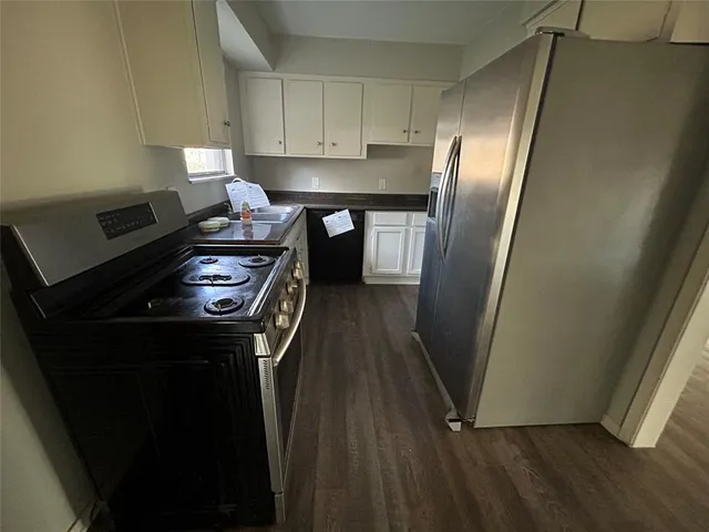 a kitchen with a refrigerator a stove and wooden floor
