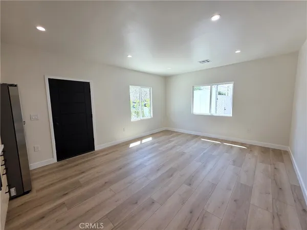 an empty room with wooden floor and windows