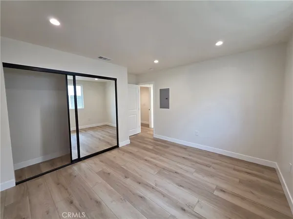 an empty room with wooden floor and mirror