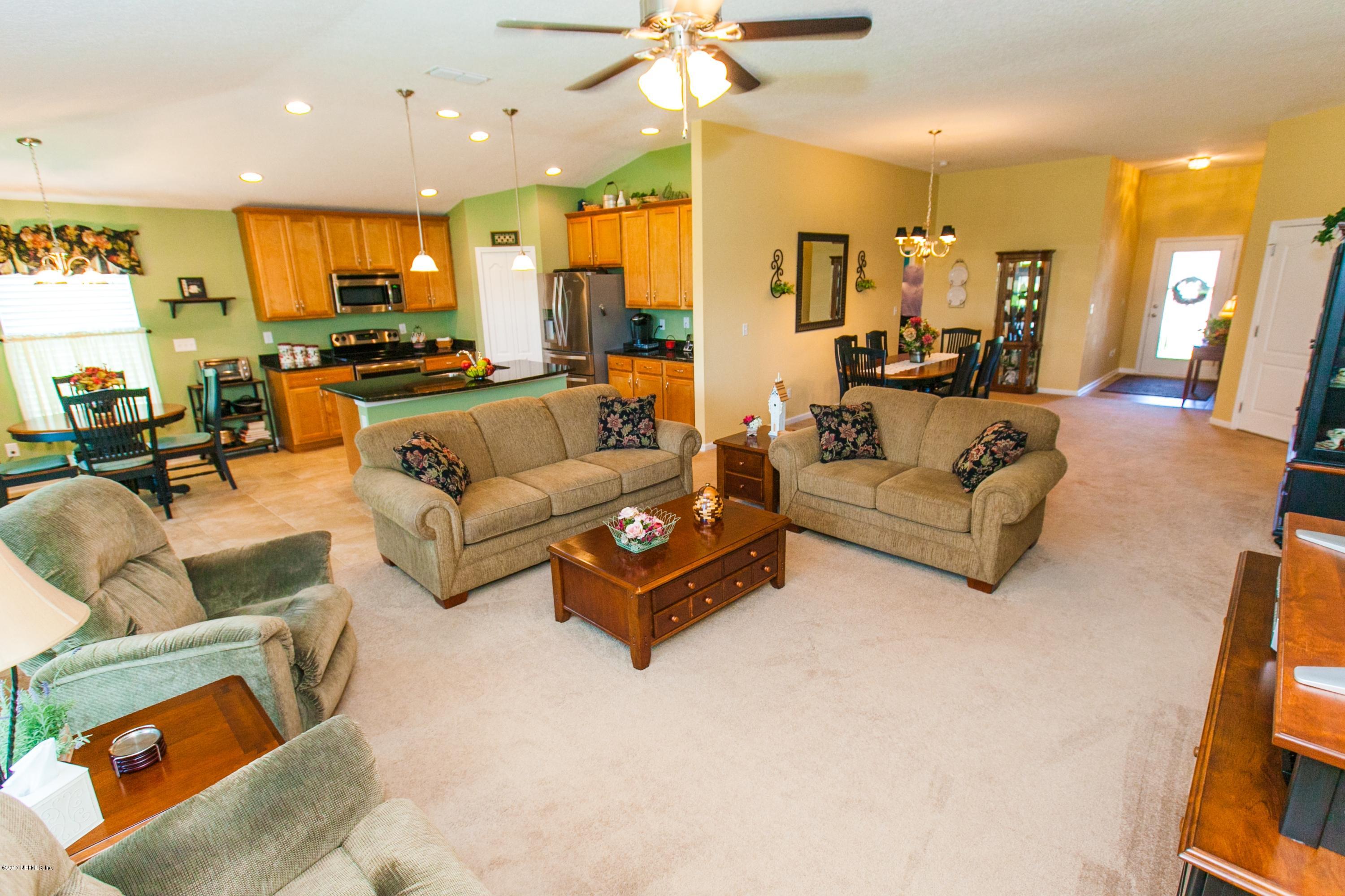 490 Irish Rose Road St. Augustine, FL 32092 - Photo 15 of 44 a living room with furniture kitchen view and a chandelier