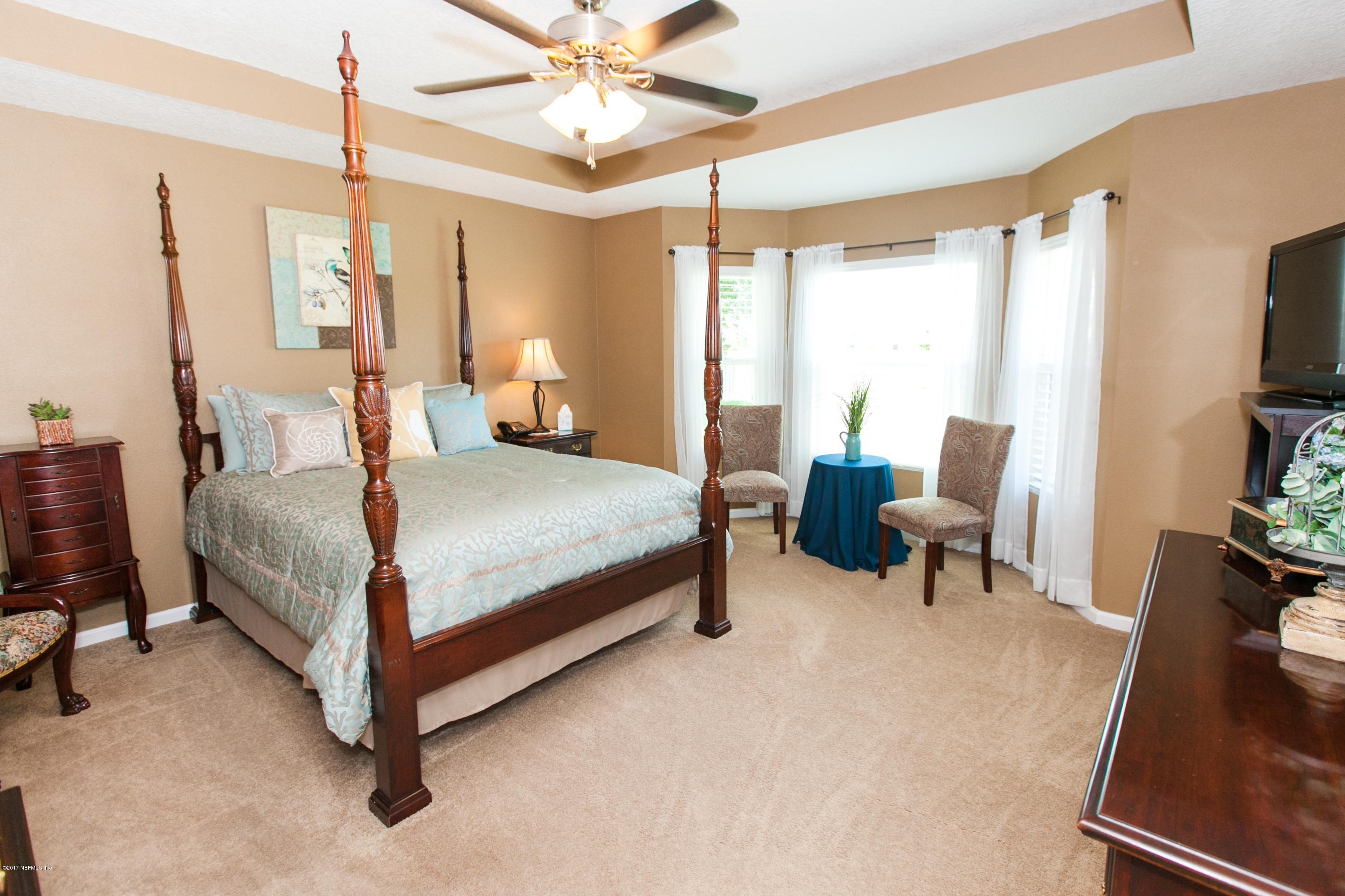490 Irish Rose Road St. Augustine, FL 32092 - Photo 17 of 44 a bedroom with a bed and a chandelier