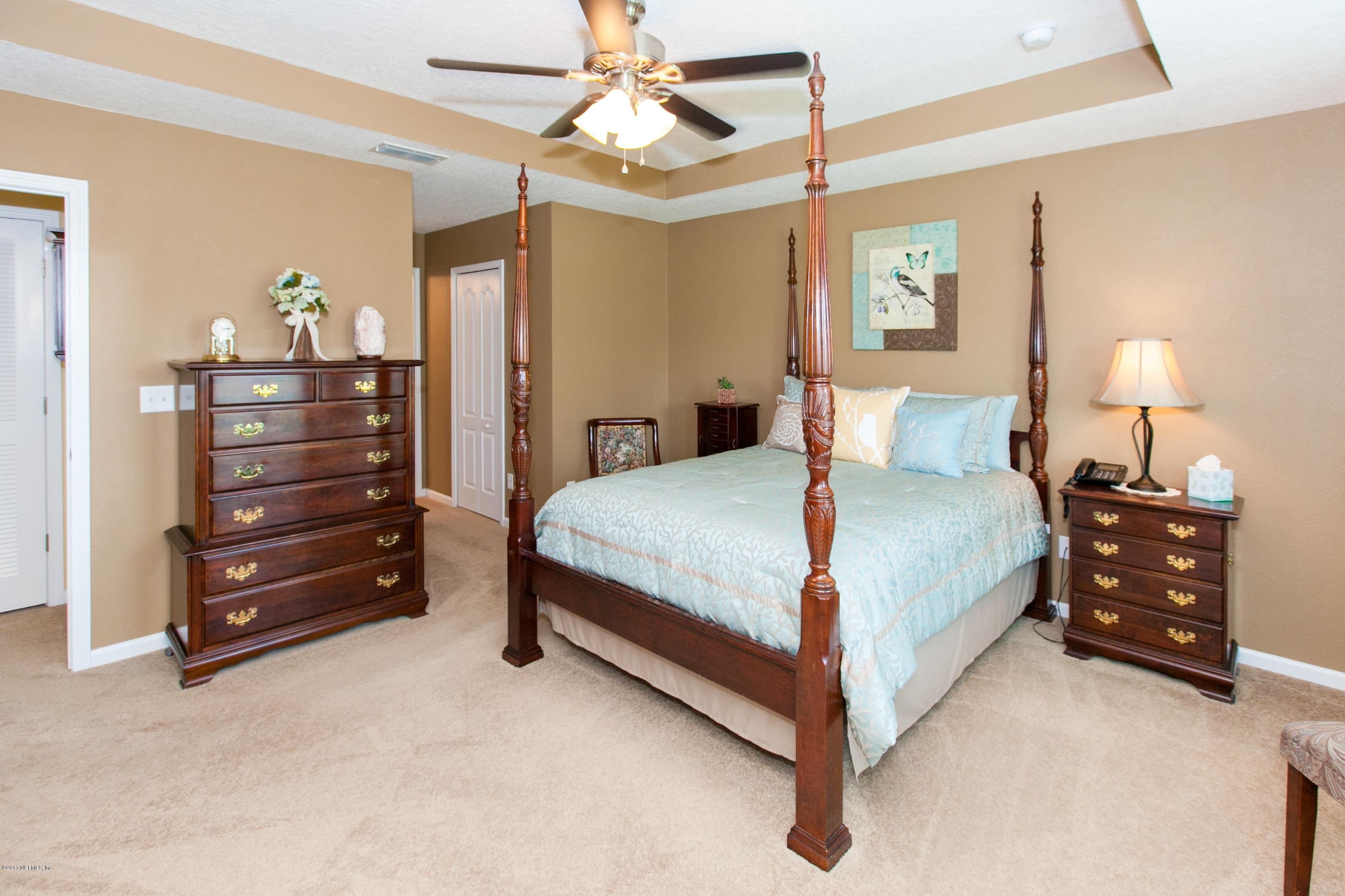 490 Irish Rose Road St. Augustine, FL 32092 - Photo 19 of 44 a bedroom with a bed and a chandelier