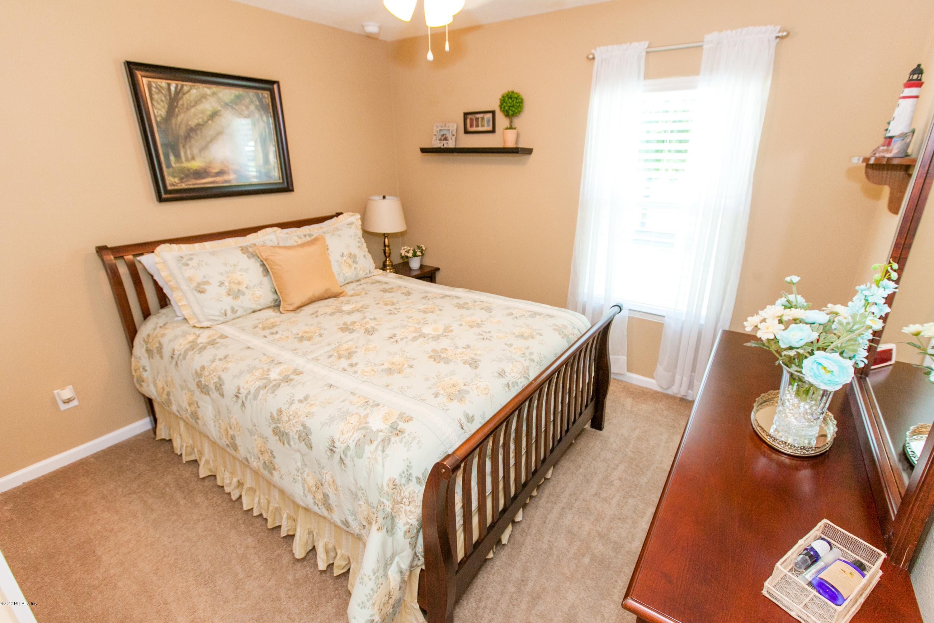490 Irish Rose Road St. Augustine, FL 32092 - Photo 22 of 44 a bedroom with bed and a chandelier