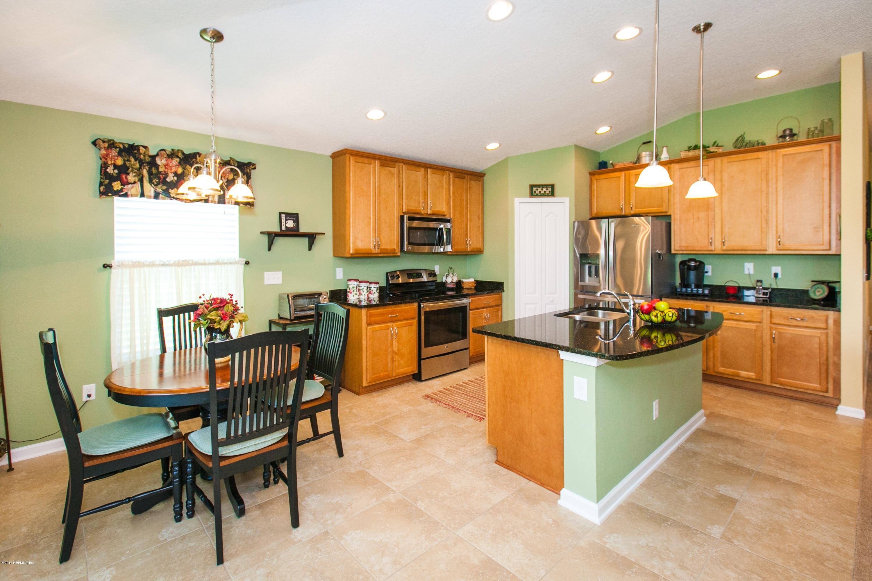 490 Irish Rose Road St. Augustine, FL 32092 - Photo 9 of 44 a kitchen with stainless steel appliances granite countertop a stove top oven a sink dishwasher and a dining table with cabinets