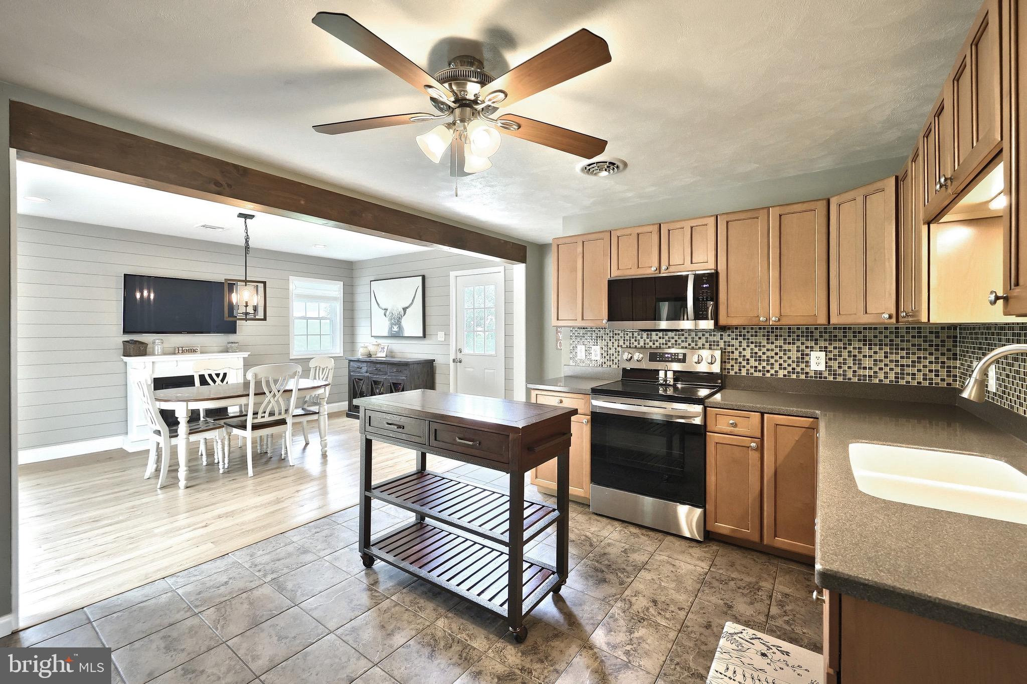2569 Emig Mill Road Dover, PA 17315 - Photo 14 of 32 a kitchen with stainless steel appliances granite countertop a stove top oven a sink dishwasher a dining table and chairs with wooden floor