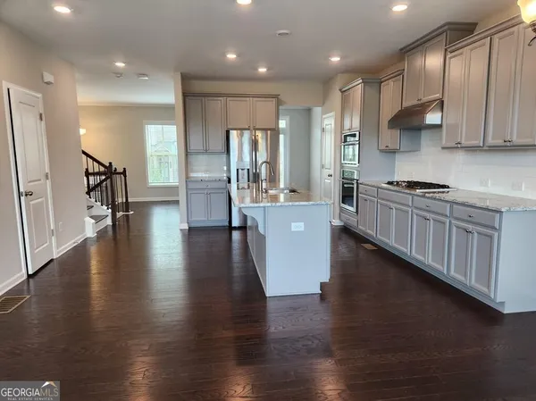 a kitchen with stainless steel appliances granite countertop wooden floors wooden cabinets and sink