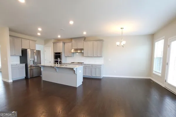 a large kitchen with white cabinets stainless steel appliances a center island and a window
