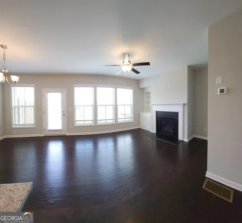 an empty room with wooden floor fireplace and windows