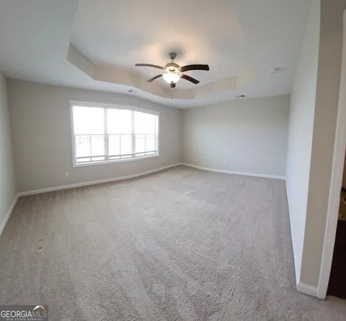 an empty room with windows and fan