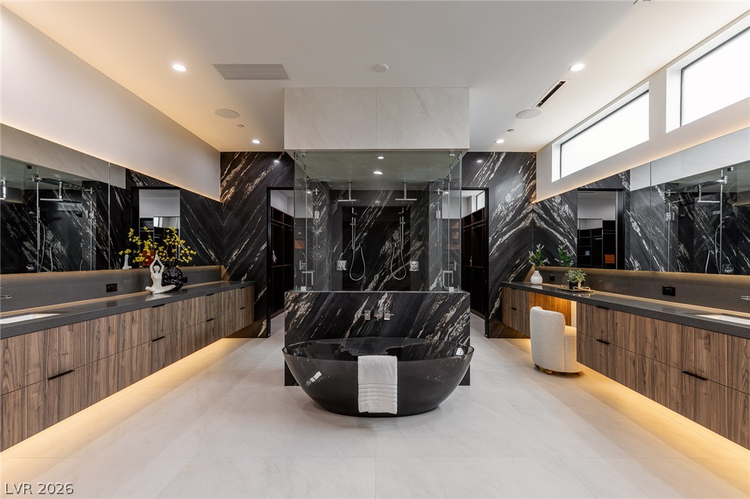 563 Grand Rim Drive Henderson, NV 89012 - Photo 23 of 70 Luxurious primary bath with sleek dark stone, floating vanities, and a central soaking tub.