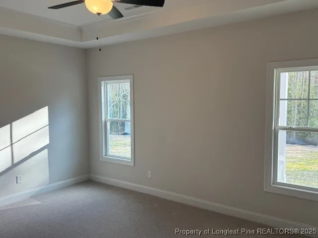 an empty room with a window and chandelier fan