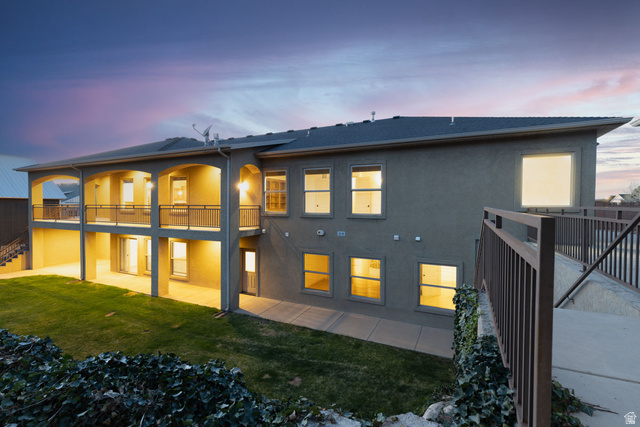 888 East Fiddlers Canyon Road Cedar City, UT 84721 - Photo 66 of 74 Back of property at dusk featuring a patio, a lawn, stucco siding, and a balcony