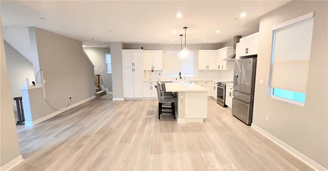 a kitchen with stainless steel appliances granite countertop a table chairs sink refrigerator and microwave