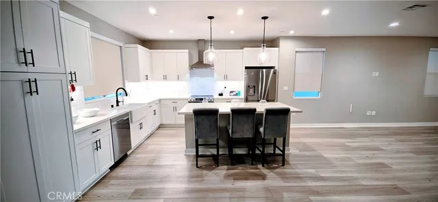a kitchen with stainless steel appliances kitchen island sink refrigerator and wooden floor