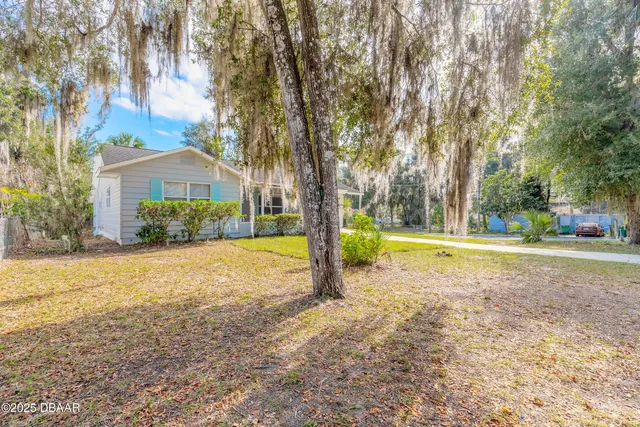 a view of a house with a yard and large trees