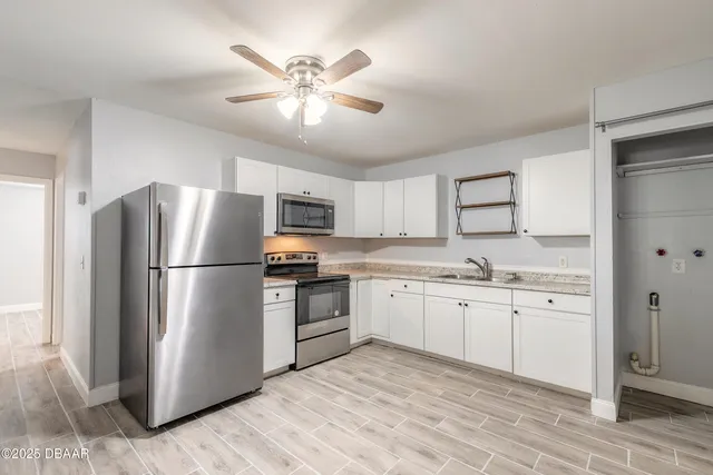 a kitchen with granite countertop a refrigerator a sink a stove and white cabinets