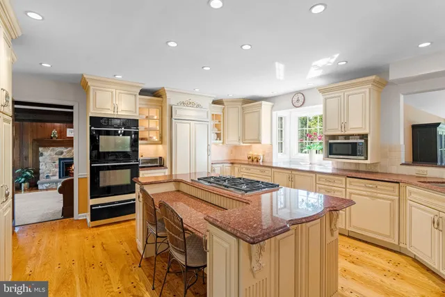 a kitchen with stainless steel appliances granite countertop a sink and stove top oven with wooden floor