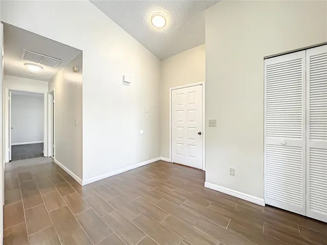 an empty room with wooden floor & windows