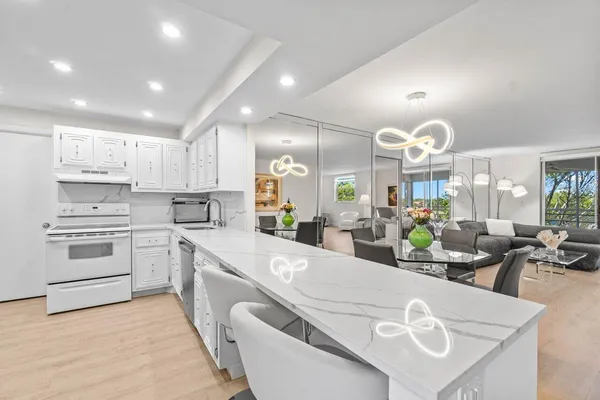 a large kitchen with kitchen island white cabinets and stainless steel appliances