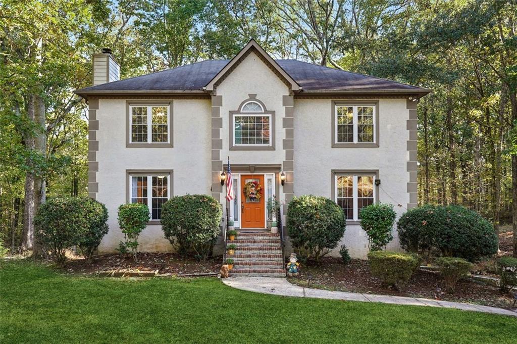 a front view of a house with a yard and trees