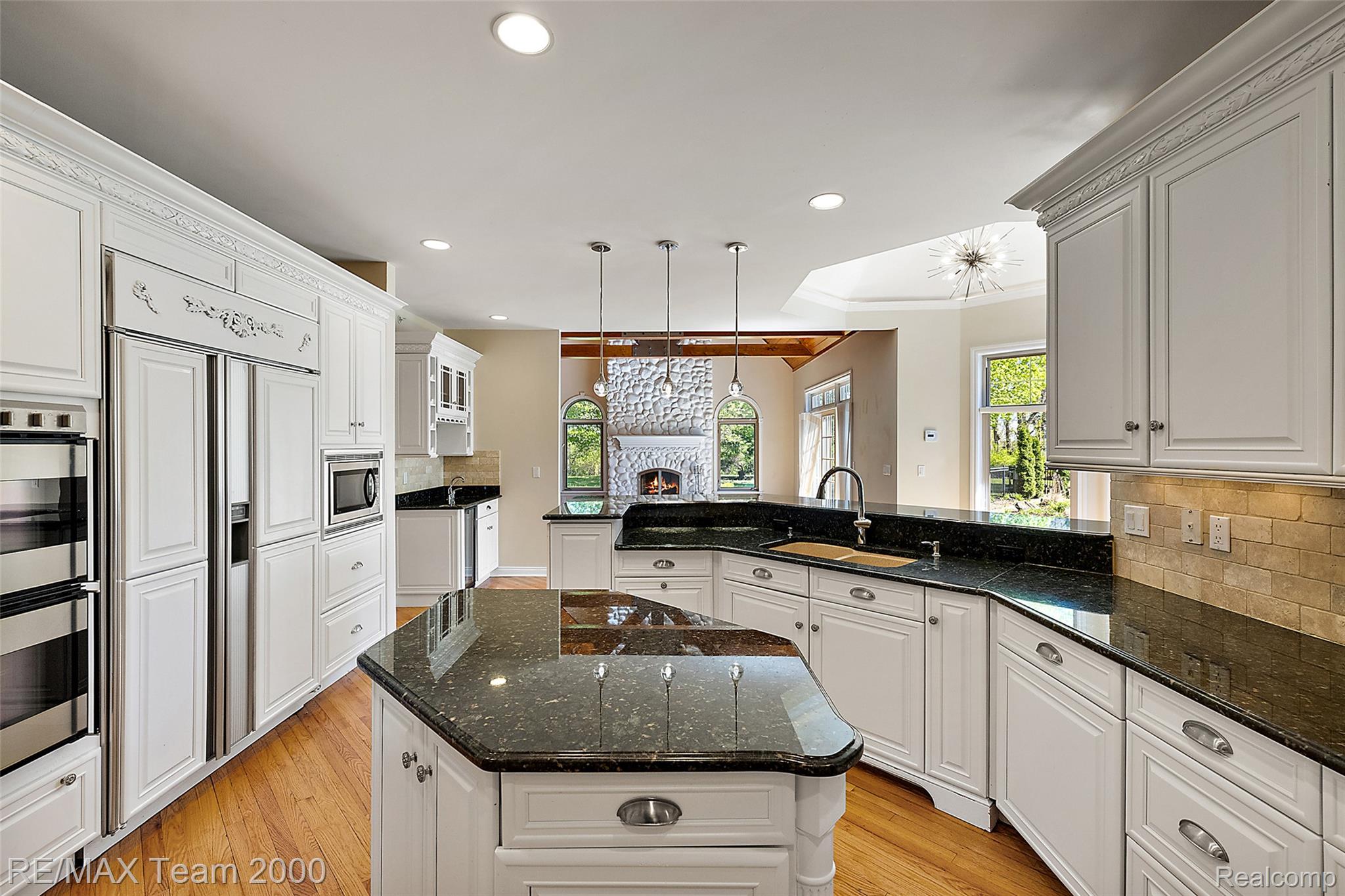 630 Sheldon Court Rochester, MI 48306 - Photo 28 of 94 Kitchen with a peninsula, a kitchen island, dark stone countertops, light wood finished floors, and ornamental molding