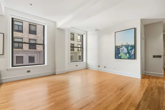 a view of an empty room with window and wooden floor