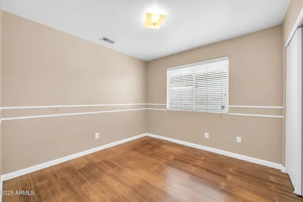 an empty room with wooden floor and ceiling fan