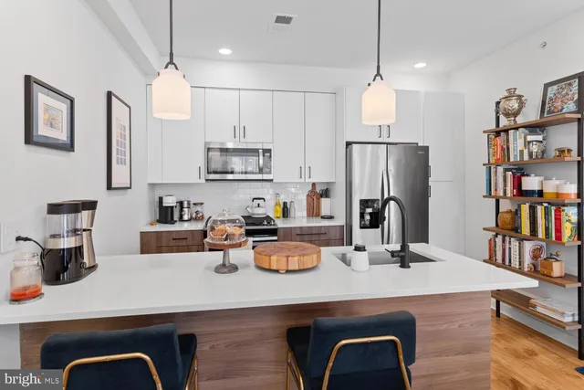 a kitchen with a refrigerator a stove a sink and a dining table with wooden floor