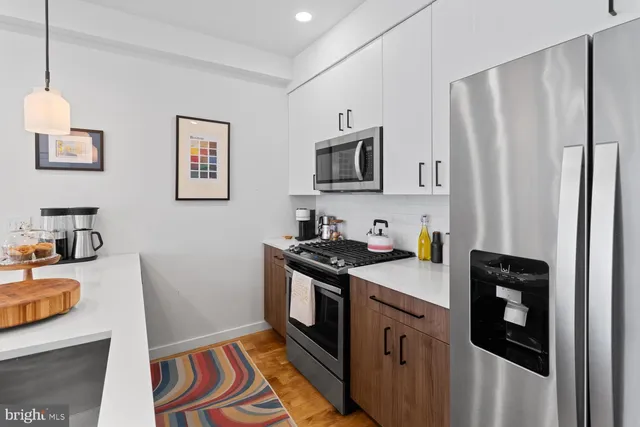 a kitchen with stainless steel appliances granite countertop a refrigerator a stove a sink and a microwave