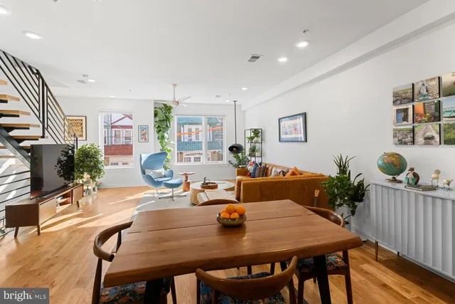 a view of a dining room and livingroom with furniture wooden floor a rug a potted plant and a painting