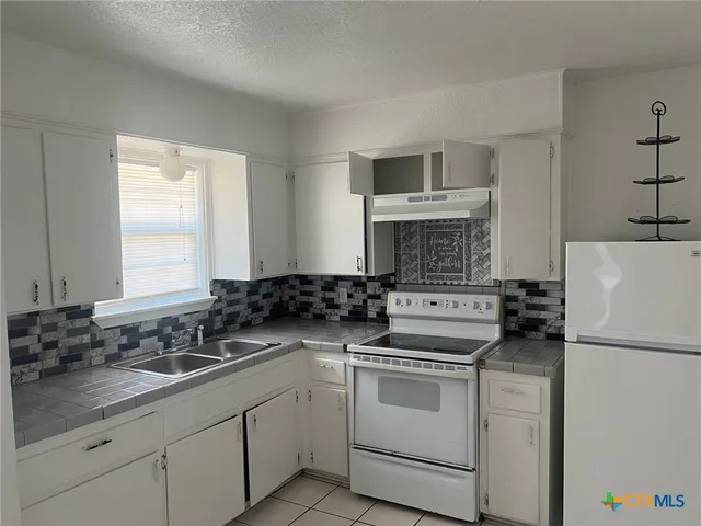 a kitchen with white cabinets sink and white appliances