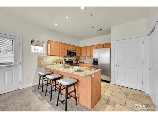 a kitchen with stainless steel appliances granite countertop a table chairs sink and cabinets