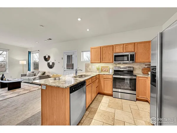 a kitchen with stainless steel appliances granite countertop a table chairs and a refrigerator