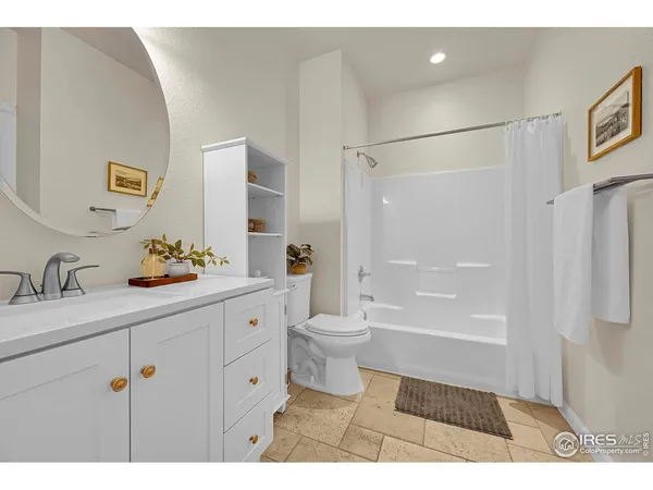 a bathroom with a granite countertop sink a toilet a mirror a vanity and shower
