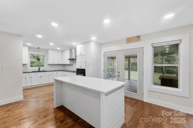 a large white kitchen with a large window and stainless steel appliances