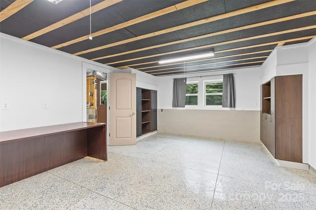 a view of an empty room with a window and kitchen