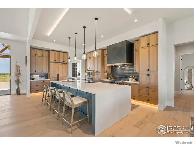 a kitchen with stainless steel appliances kitchen island granite countertop a refrigerator a stove a sink a dining table and chairs with wooden floor