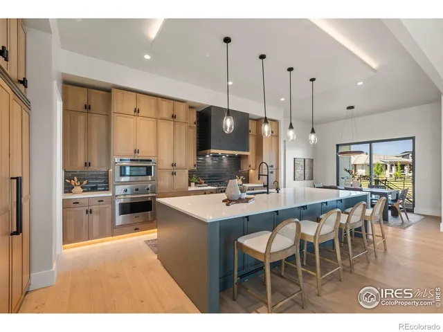 a kitchen with stainless steel appliances kitchen island granite countertop a stove a sink a dining table and chairs with wooden floor