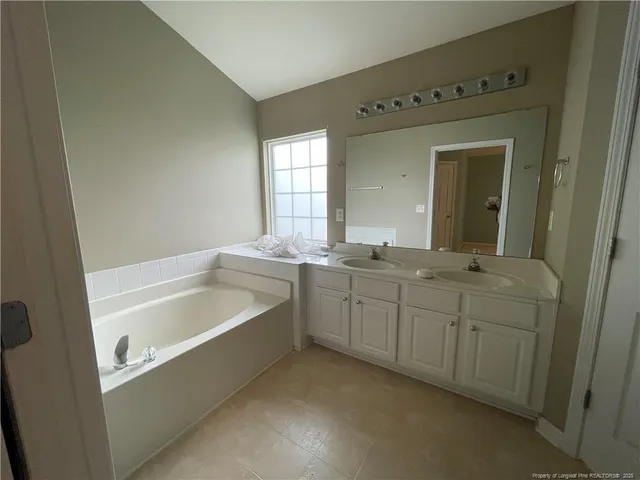 a bathroom with a tub a sink and mirror